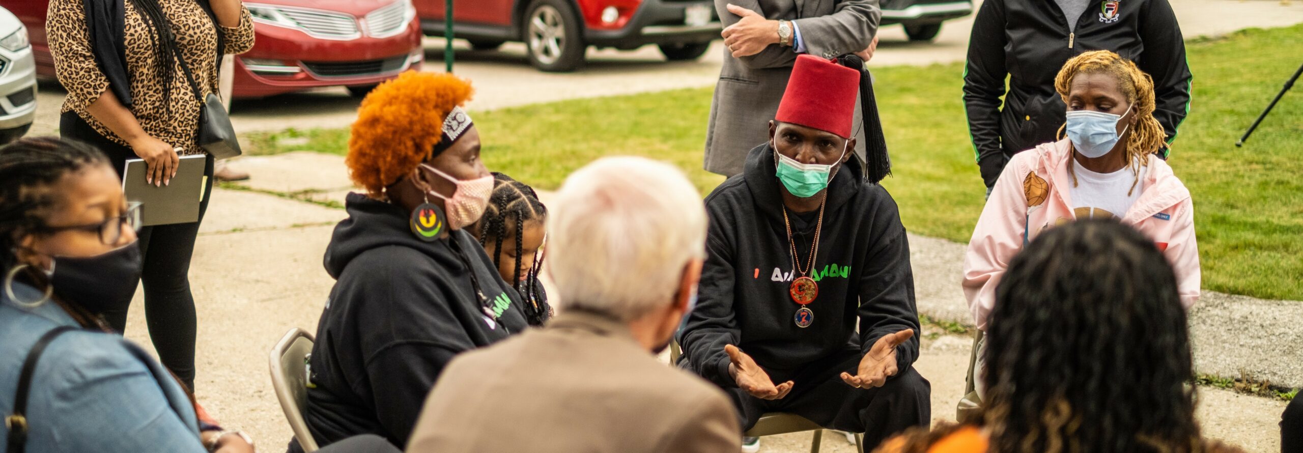 Outdoor gathering with individuals engaged in discussion in a casual park-like setting